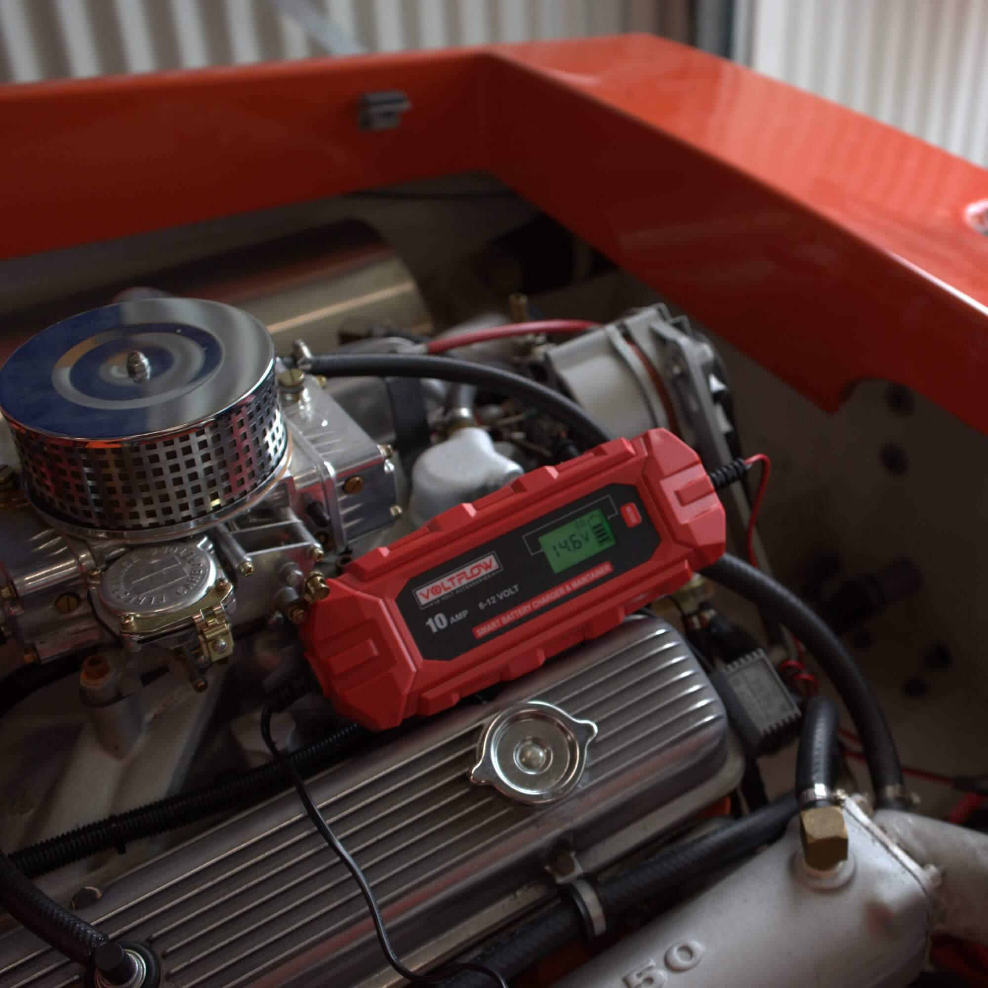 Voltflow VF10BC 12v Car Battery Charger positioned atop a refurbished classic car engine.