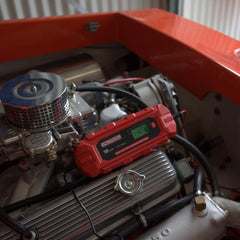 Voltflow VF10BC 12v Car Battery Charger positioned atop a refurbished classic car engine.